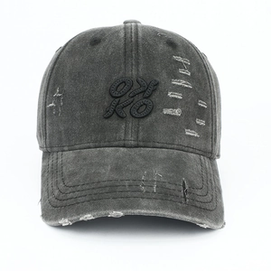 Detail of distressed dark gray washed baseball cap with frayed holes and OKKO embroidery