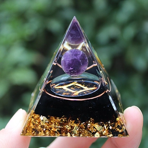Close-up of Orgone pyramid with amethyst ball, metal coil, and gold foil in resin