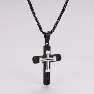 Close-up of black textured cross pendant with silver inlay on a box chain necklace