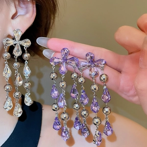 Macro shot of long crystal drop earrings in purple and clear stones with metal base