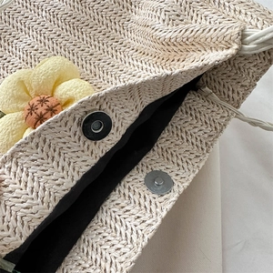 Minimalist woven straw bucket tote with magnetic closure and floral detail