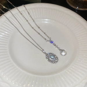 Macro shot of silver oval zircon pendant and Y-shaped crystal necklace on a ceramic tray
