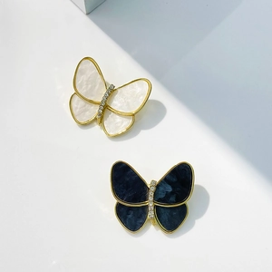 Close-up of mother of pearl butterfly brooches with gold frames and crystal details