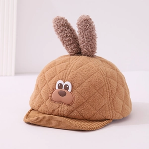 Detail of baby winter hat with plush bunny ears and cute animal patch on quilted fabric