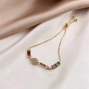 Detail of adjustable gold bracelet with colorful cubic zirconia on champagne silk backdrop