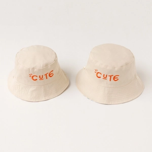 Beige cotton bucket hat for kids with orange CUTE embroidery on a white background