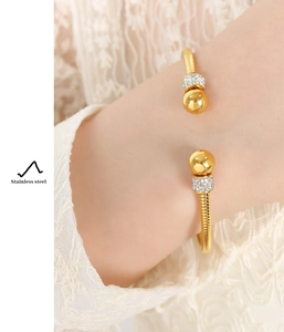 Close-up of gold-plated stainless steel cuff bracelet with sparkling zircon beads