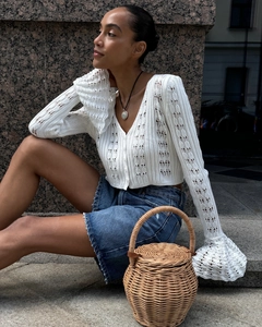 Detailed macro shot of white hollow out knit cardigan with flare sleeves and crochet texture