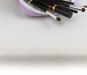 Detail of purple quilted makeup bag storing multiple brushes with a white zipper closure