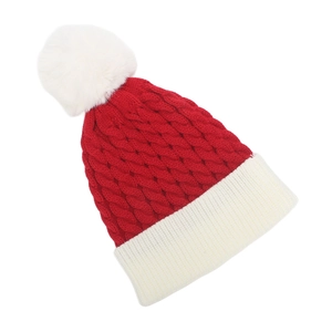 Close-up of red and white knit Christmas hat featuring thick cable weave and pom pom