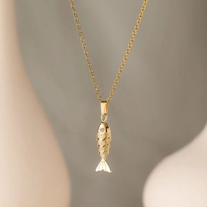 Close-up of golden fish pendant featuring textured scales and a tiny red gemstone eye