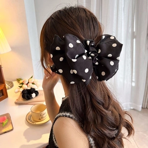 French style black and white polka dot large bow hair clip worn on model's back hair