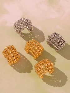 Close-up of stacked gold and silver beaded rings on a luxury marble surface