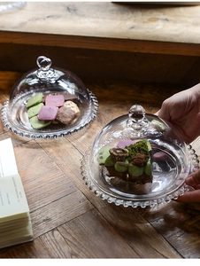 Detailansicht der Glasglocke für Desserts mit Perlenrand auf einem rustikalen Holztisch