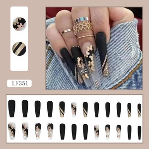 Detail view of long press-on nails with golden butterflies, glitter, and rhinestones