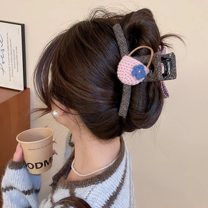 Detailed back view of a large bow hair claw clip in tweed fabric with crochet flower detail