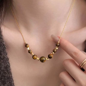 Macro detail view of tiger eye beaded necklace with gold spacers on a model's neck