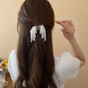 Detail of faux pearl tassel hair claw clip shown on model for a French style hair look