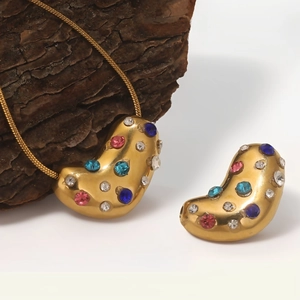 Golden pendant set with multicolor rhinestones on a rustic bark and white background
