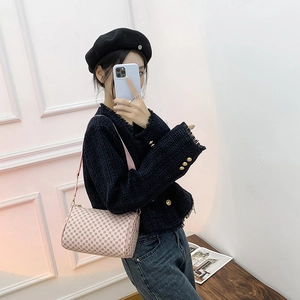 Pink cylinder shoulder bag with luxury pattern print shown on a model in a mirror selfie
