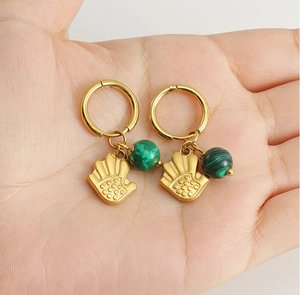 Détail de créoles dorées 18k avec pendentif paume et malachite verte présentées sur une main
