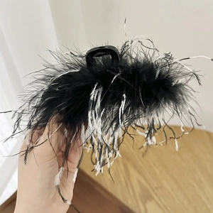 Close-up of fluffy black ostrich feathers with white accents on a large hair claw clip