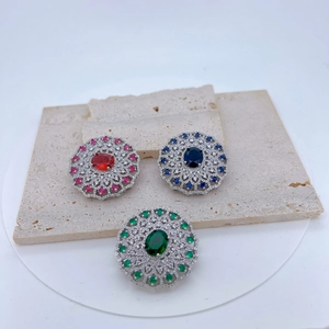 Vintage round brooch set with red, blue, and green stones in silver finish