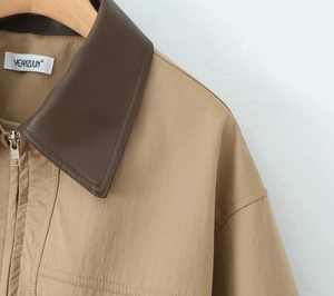 Detail of khaki jacket showing brown leather collar and silver metallic zipper