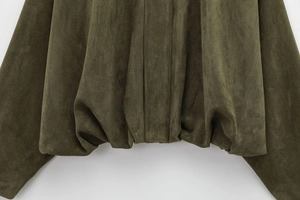 Detailed close-up of dark green suede bomber jacket showing fabric texture and hem folds