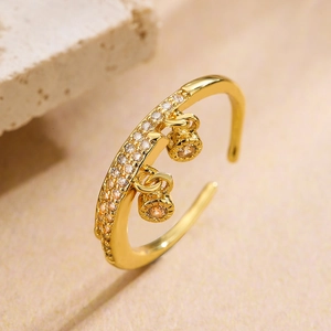 Detail of gold-plated open ring featuring pavé zircons and two elegant round charms