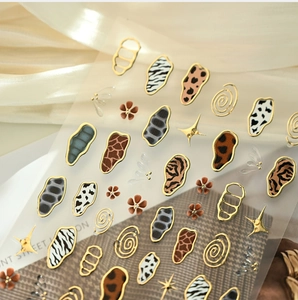 Close-up of animal print nail stickers with metallic gold stars and textured patterns