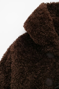 Detail of deep brown faux fur coat showing plush texture and leather knot button fasteners