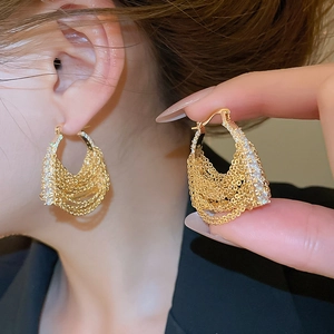Close-up of gold plated tassel earrings with zircon-encrusted U-shaped chain design