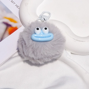 Detailed view of grey fuzzy monster keychain with large eyes and blue sausage lips