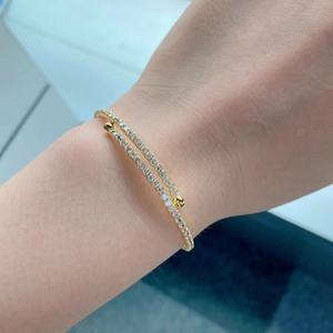 Detail of double-layered gold bracelet with white zircons and spherical metal ends