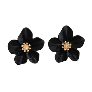 Close-up of black floral stud earrings with gold center and matte finish petals