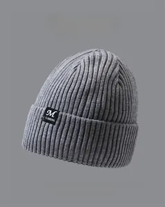 Detail view of ribbed knit beanie with woven letter tag and multiple color options