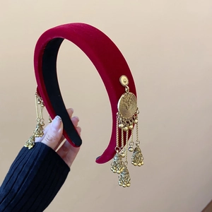 Close-up of red velvet headband featuring ethnic style golden metallic tassel charms