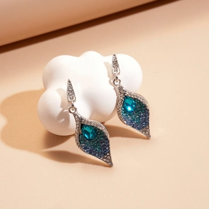 Detailed shot of leaf-shaped silver earrings set with blue and cyan crystals