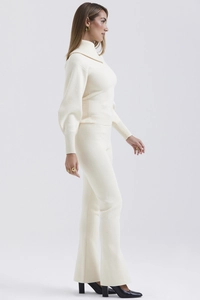 Detail of cream white knitted set showing high-neck long sleeve sweater and wide-leg trousers