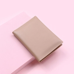 Close-up of beige PU leather wallet with fine stitching on a pink geometric stand