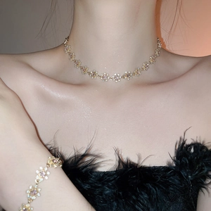 Close-up of gold flower pendant necklace and bracelet set with sparkling crystals