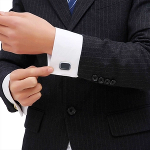 Close-up of a man wearing classic silver-edged black cufflinks on a white shirt sleeve