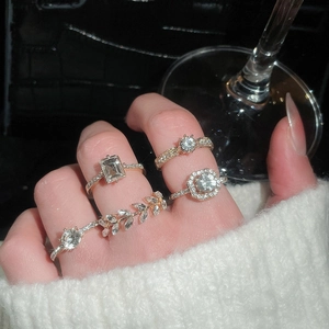 Detailed view of five gold zircon rings set with geometric and leaf designs on a hand