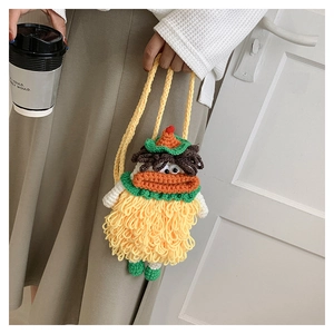 Detail of a handmade yellow knit crossbody bag with a funny sausage mouth character design