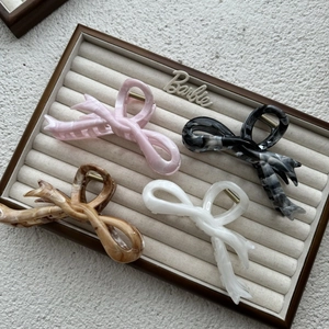 Macro detail of four marble pattern hair claws in pink, black, brown and white resin