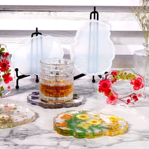 Macro view of irregular silicone coaster molds with floral resin crafts on marble