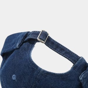 Detail of blue denim docker hat showing silver metal adjustment buckle and twill fabric