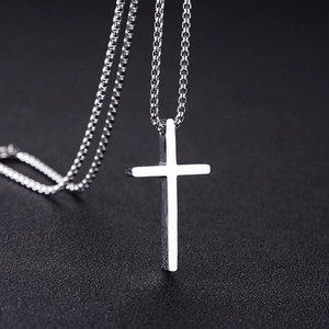 Classic silver stainless steel cross necklace for men on a black textured background