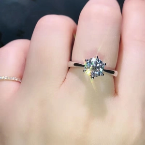 Macro shot of silver ring featuring classic six-prong moissanite setting and brilliant fire